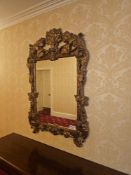 A Italian Rococo Revival style composite mirror featuring a heavily carved and moulded frame