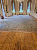 A large, rectangular wool carpet The central field, predominantly a light green-teal, is patterned
