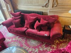 A classic camel back upholstered sofa in deep red velour upholstery gently scrolled back and