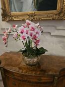 A faux Phalaenopsis orchid arrangement, featuring numerous pink and white artificial blooms, green