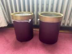 A pair of cylindrical waste bins, each wrapped in burgundy-coloured leather and finished with a