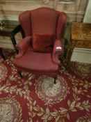 A pair of traditional-style wingback armchairs, upholstered in a textured red chenille type fabric