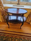 A Rococo Revival two-tiered oval mahogany occasional table crafted from a dark-stained wood,
