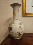 A large glazed ceramic vase features a baluster-form body and a flared neck, resting on an off-white