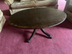 An elegant Regency-style oval coffee table in mahogany, featuring a contrasting lighter wood band