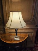 A Neoclassical style table lamp the base is constructed from a patinated finished metal, featuring a