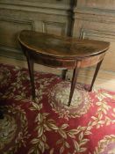 A Walnut veneer folding card table, presenting as a demilune console when closed and converting to
