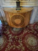 A Neoclassical-style demilune cabinet, attributed to Baker Furniture, crafted from veneered wood