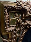 A large, giltwood frame decorative mirror The frame features intricate detailing, including