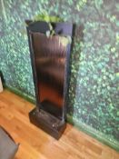 Vertical indoor water feature with dark textured cascade panel and integrated pump system.