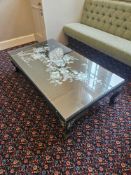 Rectangular coffee table with glass top over a decorative panel featuring a peacock motif inlaid