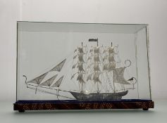 An Eastern handmade white metal filigree model three-masted schooner in glass presentation case: