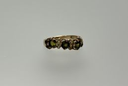 A 9ct gold ring set three circular cut peridots with four pairs of small peridot spacers: l. x 2.