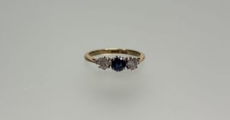 An 18ct gold ring set circular faceted sapphire approximately 0.3ct flanked by a brilliant cut