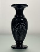 A decorative black marble pedestal vase, with carved circular floral band to centre. (h-25.5cm)