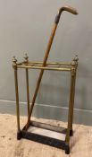 An Edwardian brass stick stand, with eight dividers and brass urn finials to top, over a cast iron