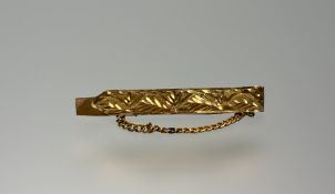 A Middle Eastern yellow metal tie clip with engraved panel to the front and safety chain: l. x 5cm