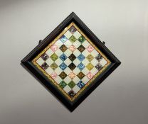 An early 20thc polychrome reverse painted on glass chess board with a foliate border, presented in a