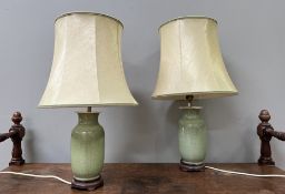 A pair of Chinese porcelain celadon table lamps raised on wooden stands, complete with cream silk
