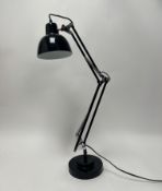 A modern black angle poise desk lamp with adjustable arm, raised on a stepped base (plug removed) (