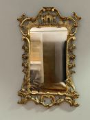 An 18thc gilt wood rococo mirror with s scroll and c scroll carved wood frame, with rose and leaf