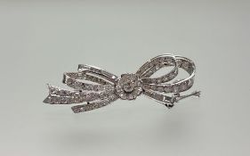 A diamond bow brooch, 20th century, centred by a flowerhead and set throughout with round