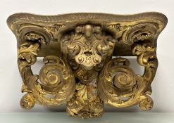 A large 19th century giltwood and composition wall bracket, the baize-lined serpentine shelf