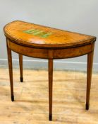 A Regency satinwood and mahogany crossbanded demi lune foldover card table with painted roman