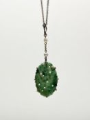 A jade pendant, the oval carved plaque claw-set in unmarked yellow metal and suspended from a