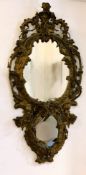 A 19thc Continental gilt wood and composition double plate oval mirror in high rococo taste, with