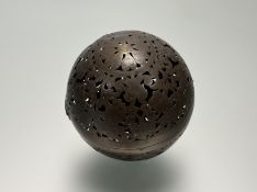 A 19th century reticulated spherical patinated metal incense burner, probably Chinese, decorated