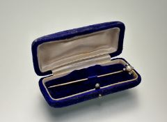 A late 19thc gold stick pin set with a natural pearl within a surround of four rose-cut diamond