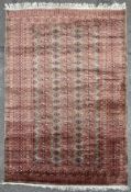 A hand-knotted Turkman Bokhara rug, central field with three rows of repeating gol motif, enclosed