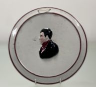 A 19thc Pottery Plate with a mouled head and shoulders portrait of a man, with burgandy painted