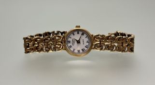 A modern 9ct gold lady's quartz wristwatch with white enamel dial and roman numerals on 9ct gold
