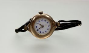 A vintage 9ct gold wristwatch with white enamel dial and Roman numerals workinng on original black