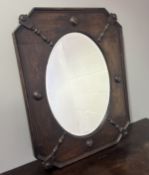 An Arts and Crafts dark stained oak oval framed mirror with bevelled glass panel (h. 73cm)