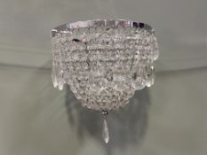 A collection of three two-tiered hanging chandeliers with chrome frames and clear acrylic drops (