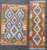 A set of two kilim rugs, each with stylized diamond medallions surrounded by geometric motifs, green
