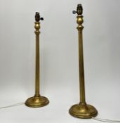 A pair of gilded carved wooden table lamps of corinthian form, raised on circular bases (h. 61cm) (