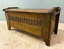 A modern stained oak blanket chest, with shaped sides and carved panel to front, hinged top and
