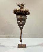 A Zaire carved wooden mask raised on a metal and wooden stand, with woven detail to top and rope and