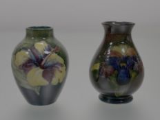 A pair of Moorcroft Pottery bud vases, one in a hibiscus on green ground (h-10cm) the other a
