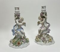 A pair of Sitzendorf porcelain candelsticks decorated as cherubs with polychrome floral decoration
