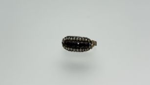A 19thc yellow metal ring set six pink faceted cut foiled stones within a surround of seed pearls
