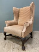 An Edwardian wingback armchair, with shaped top and roll arms, upholstered in a geometric