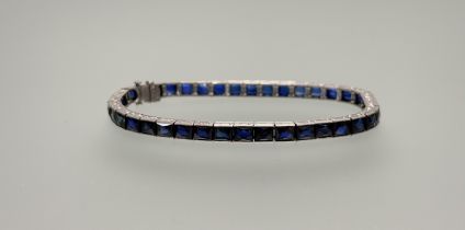 A white metal blue paste set line bracelet with clip fastening: d. x 7cm