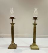 A Neo-Classical style pair of cast brass and glass Corinthian form candlesticks, the square