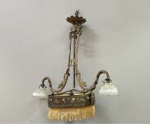 An early 20thc patinated metal pendant chandelier with silk fringe, scrolling foliate embellishments