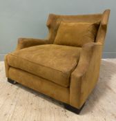 A contemporary wingback armchair by Orior, with curved back and seat cushions, upholstered in tan